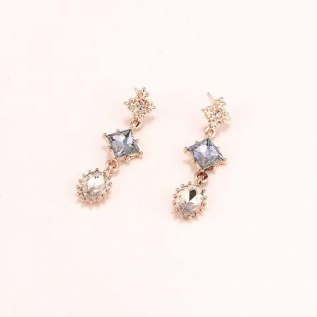 Gros plan sur les boucles d'oreilles géométriques pendantes avec des pierres précieuses en forme d'étoile et rondes.