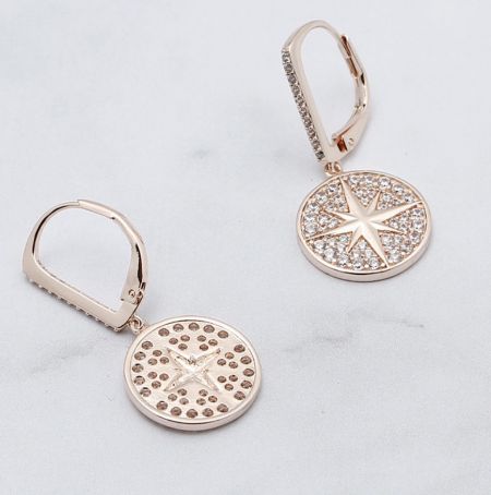 Une paire de boucles d'oreilles Sunburst Drop posées à plat sur une surface blanche, mettant en valeur l'artisanat détaillé et les pierres scintillantes.