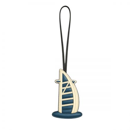 A unique sailboat-shaped leather charm in blue and cream, representing Dubai's coastal luxury.