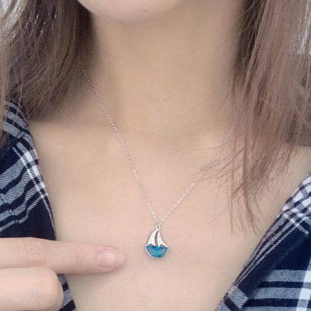 A model wearing the sterling silver sailboat pendant necklace, showcasing its length and style.