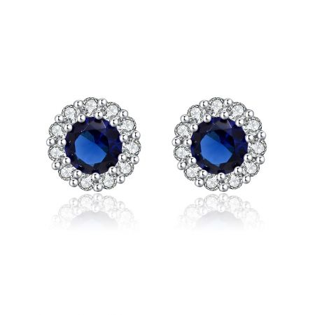 Boucle d'oreille en rhodium Montana - Un gros plan de la boucle d'oreille en rhodium Montana, mettant en valeur la pierre en verre Montana bleu profond entourée d'un halo brillant de zircon cubique blanc, montée en laiton plaqué rhodium.