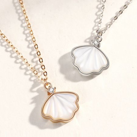 Collar con colgante de concha marina de plata esterlina 925 - Un par de collares de colgante de concha marina de plata esterlina 925, uno con un acabado de plata pulida y el otro en un tono dorado cálido, exhibidos uno al lado del otro.