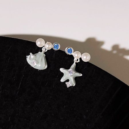銀メッキの非対称な星の砂と貝殻のスタッドピアス（5ペアセット） - 星の砂や貝殻のデザインに真珠と青いジルコンのアクセントが施された、海をテーマにした銀メッキのスタッドピアス5ペアのコレクションが白い表面に展示されています。