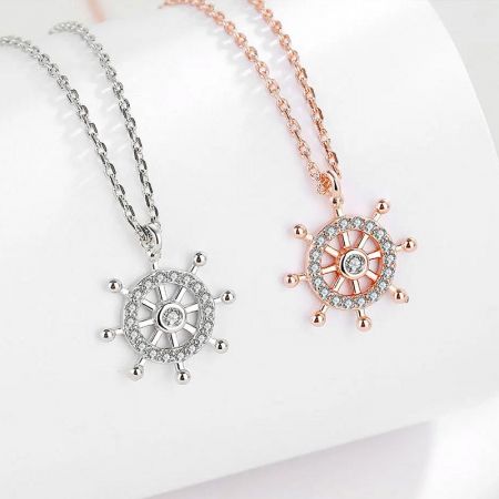 Collar con colgante de timón de barco de plata de ley 925. - Un conjunto de collares de viaje oceánico de plata de ley 925, que muestra tanto los colgantes de timón de barco de plata como de oro rosa con acentos de piedras brillantes.