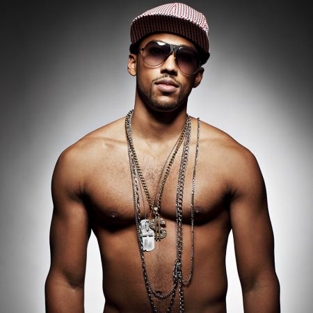 Male model showcasing bold hip-hop accessories, including chains and rings.