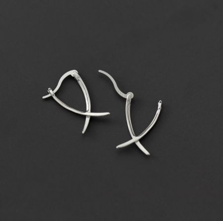 Una vista ravvicinata dettagliata degli orecchini a pendente a croce semplice in argento sterling 925, evidenziando la texture e la finitura.