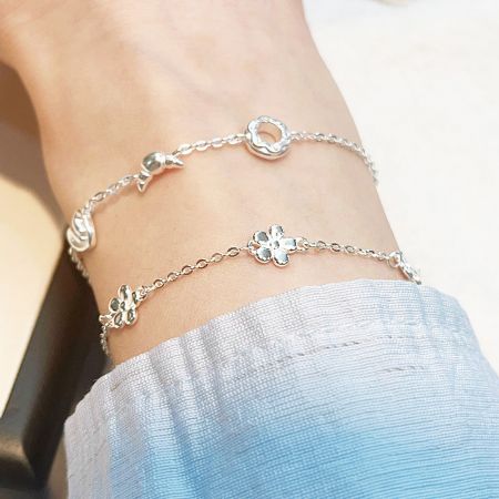 Pulseras de charm de flor y disco de plata esterlina versátiles usadas como tobilleras.