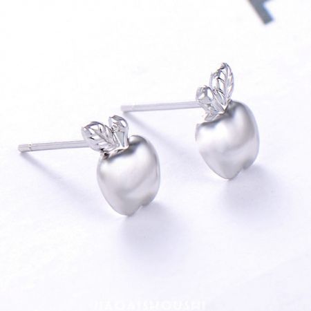 Vista ravvicinata degli orecchini a bottone a forma di mela in argento sterling 925 lucidato, che evidenzia il design della foglia.