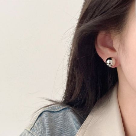 シルバーの12mmボールスタッドピアスを着用した女性のクローズアップで、そのクラシックなスタイルを強調しています。