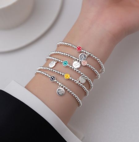 925 Sterling Zilveren Glimlach Elastische Kralenarmband - Een collectie van 925 Sterling Zilveren Glimlach Elastische Kralenarmbanden met kleurrijke emaille charmes, weergegeven op een neutrale achtergrond. Model JRSH-011 van JR Fashion Accessories.