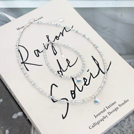 Conjunto de 5 pulseras de cadena de perla y cuentas de vidrio con charm de corazón de esmalte de plata esterlina 925 al por mayor. - Un par de pulseras de plata esterlina 925 de un conjunto al por mayor, con delicadas cuentas de perla y vidrio y un charm de corazón de esmalte azul y blanco en el centro.