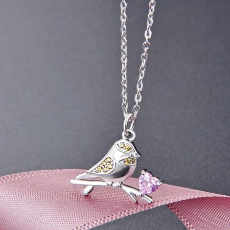 Collares tipo choker con colgante de pájaro gorrión de zircon en forma de corazón rosa de plata esterlina 925. - Primer plano de un collar con colgante de pájaro gorrión de plata esterlina 925, detallado con un zircon en forma de corazón rosa y acentos de piedras preciosas amarillas.
