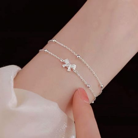 Close-up view of the double-layer 925 silver bracelet with a delicate bow charm.