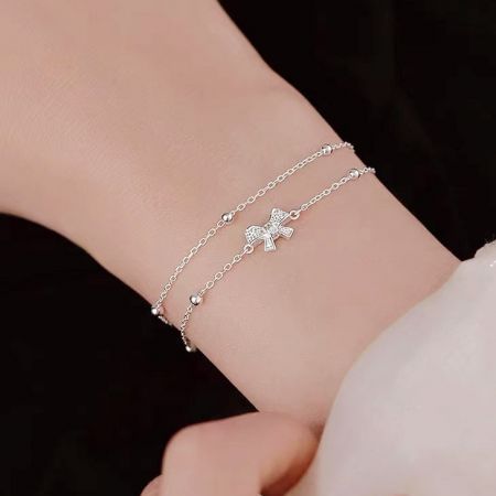 Detailed shot of the coquette bow charm on the sterling silver bracelet.