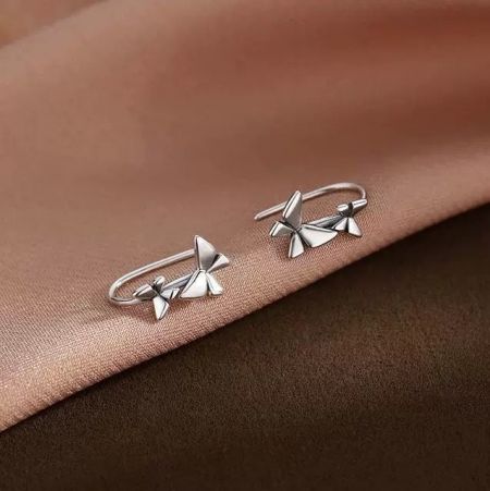 Un paio di orecchini a gancio a forma di fiocco in argento sterling del set di design creativo, mostrati su una superficie testurizzata.
