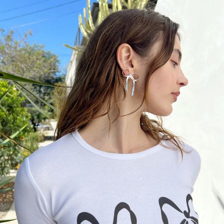 Model met de zilveren roestvrijstalen strikoorbellen, die benadrukken hoe ze een outfit aanvullen.