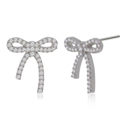 Une paire de boucles d'oreilles en forme de nœud papillon en argent, l'une montrant le tige pour l'attache, mettant en valeur le savoir-faire.