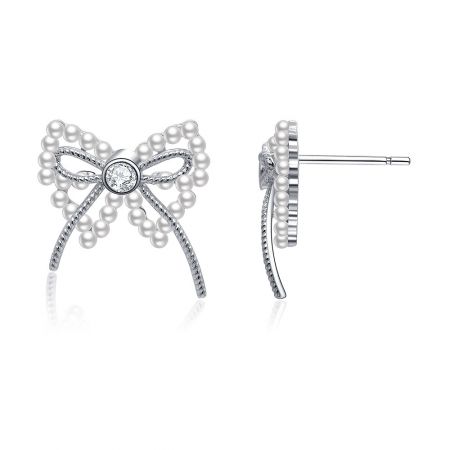 Vue latérale détaillée de la boucle d'oreille en forme de nœud en ruban de perles, mettant en valeur le plaquage en rhodium et la monture de la perle et du zircon cubique.