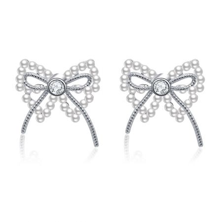 Boucles d'oreilles percées en forme de nœud en ruban de perles - Une paire de boucles d'oreilles percées en forme de nœud en ruban de perles en laiton plaqué rhodium, mettant en valeur le design complexe du nœud avec une perle blanche centrale et des accents de zircon cubique étincelants.