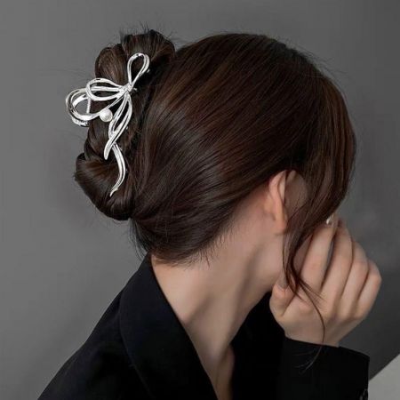 A woman with a dark brown bun wearing the large silver ribbon hair clip with a pearl detail.