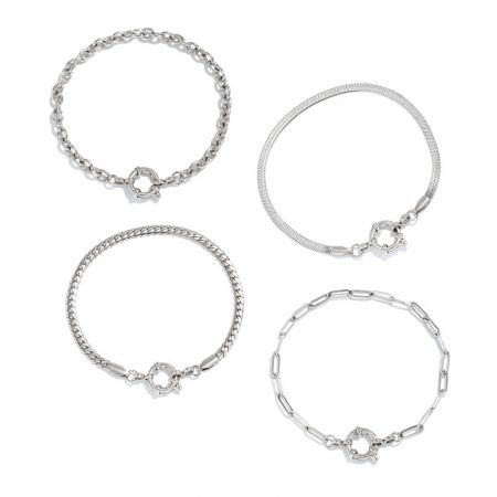 白い表面に展示されたスタイリッシュな銀メッキのステンレススチールチェーンブレスレットのセット。