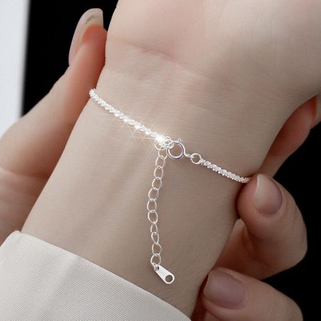 Vista lateral del brazalete de plata de ley en la muñeca de un modelo.