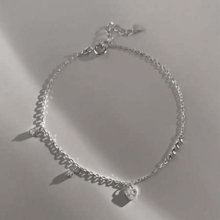 Close-up of the dainty silver bracelet showcasing the trio of polished mini heart beads and cubic zirconia charms.