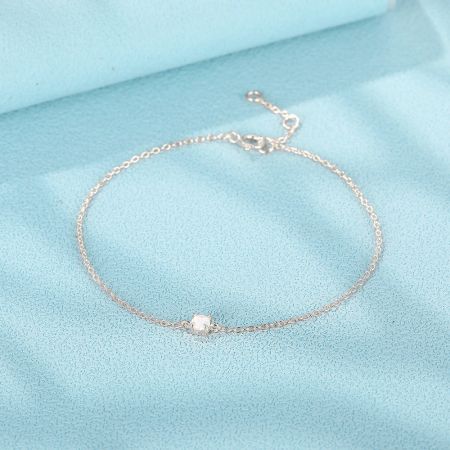 Scatto del prodotto del bracciale argentato con un singolo piccolo gemma in opale bianco.