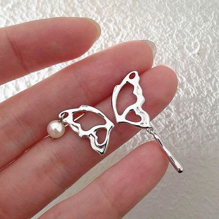 Scatto dettagliato dell'orecchino a forma di farfalla in argento sterling 925 con una singola perla.