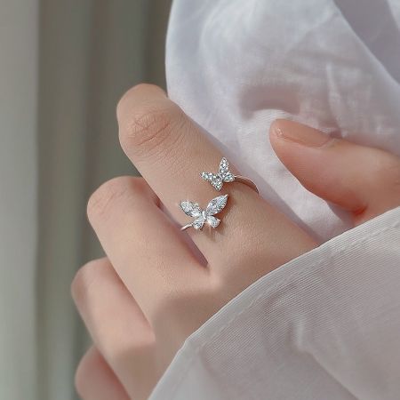 Anillo de mariposa doble ajustable en plata esterlina usado en un dedo para mostrar la escala.
