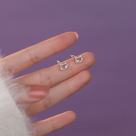 Boucles d'oreilles en argent sterling en forme d'oreilles de chat avec des zirconias cubiques scintillants, présentées sur un tissu rose doux pour un look de cadeau festif.