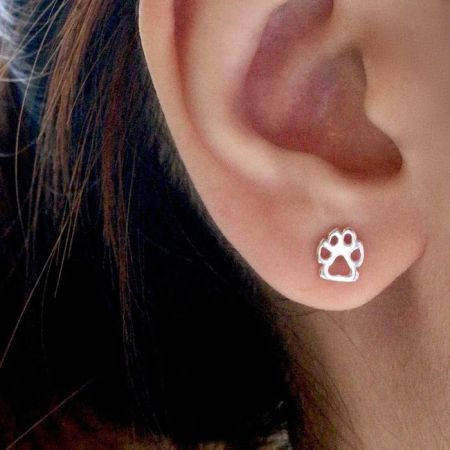 Primo piano di un orecchino a perno con impronta di zampa in argento sterling indossato.