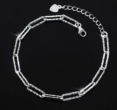 Detalhe do fecho em forma de coração seguro da pulseira de corrente prateada.