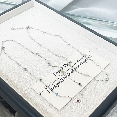 Deux colliers en argent sterling avec charms en CZ présentés sur une carte de présentation, idéaux pour offrir ou pour la vente au détail.
