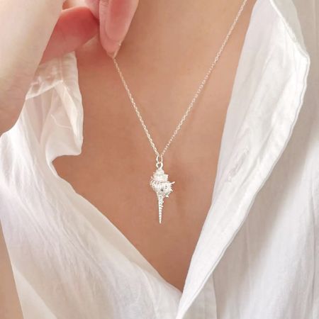 A close-up view of the seashell pendant necklace being worn, highlighting its delicate details and silver finish.