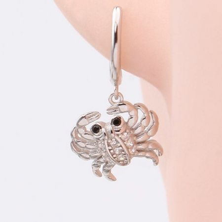 Primo piano dell'orecchino huggie con granchio in argento 925 argento sterling, mostrando l'accurata lavorazione e le pietre scintillanti.