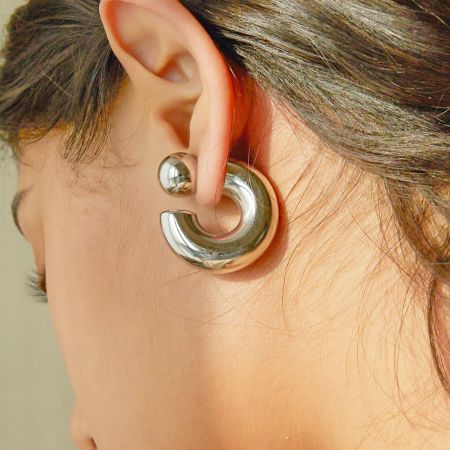 Macro view of the silver crescent-shaped earring, highlighting its polished finish.