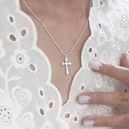 Collier pendentif croix en argent sterling 925 de gros de 20 mm - Une femme portant un élégant collier pendentif croix en argent sterling 925, mettant en valeur sa chaîne délicate et son design classique contre un haut en dentelle blanche.