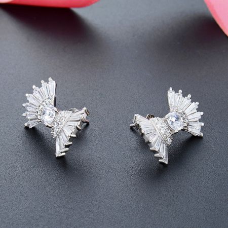 Primo piano dettagliato degli orecchini a forma di fiocco in argento che mostrano le intricate decorazioni in cristallo.