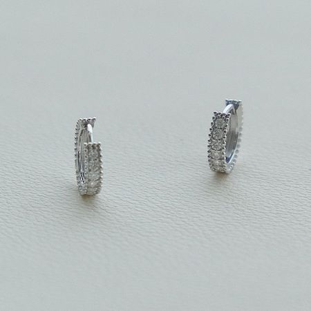 Vista dettagliata degli orecchini huggie in argento sterling 925 che evidenziano le brillanti pietre di zirconia cubica.