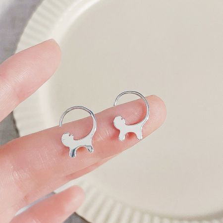 手に持たれた銀色の犬の形をしたイヤリングのペア。