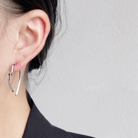 Perfil lateral de un modelo que muestra los elegantes pendientes de corazón plateados.
