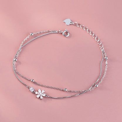 The silver double-strand bracelet worn on the wrist, highlighting its delicate design.