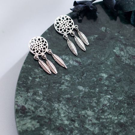 Vue de face de la paire de boucles d'oreilles attrape-rêves en argent sur fond blanc.