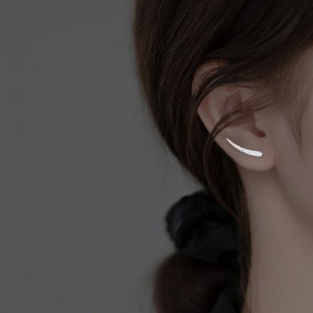 Primo piano di un orecchino climber in argento sterling con una superficie testurizzata unica.
