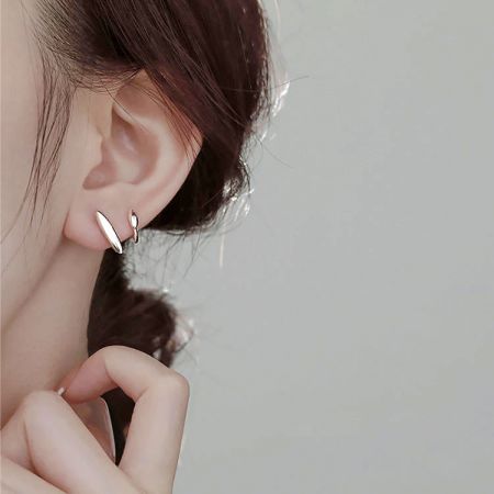 Dettaglio ravvicinato di un orecchino a cerchio in argento sterling su uno sfondo bianco.
