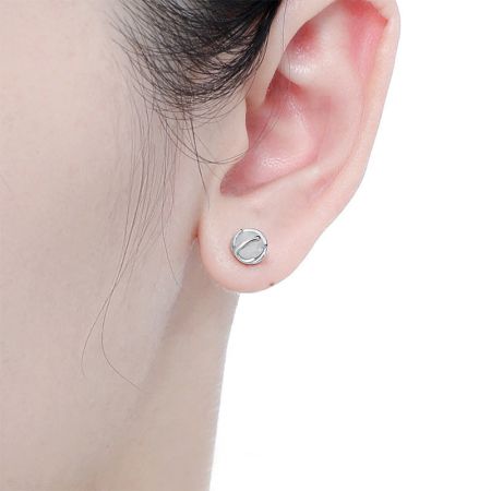 Primo piano dell'orecchino a perno in argento sterling con agata bianca indossato su un orecchio, che dimostra la sua dimensione e vestibilità.