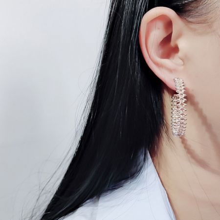 Una versión chapada en plata de los aretes de aro texturizados, elegantemente usados para mostrar su tamaño y estilo.