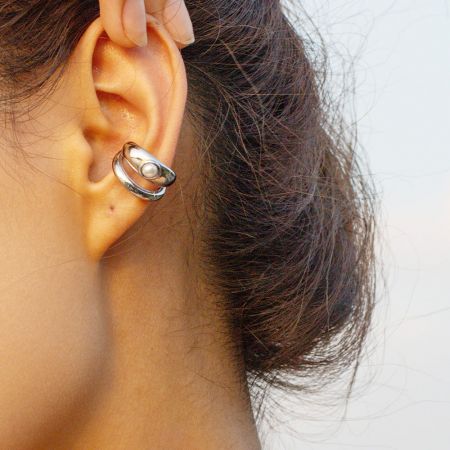 Primer plano del arete de perla de acero inoxidable plateado usado en una oreja.
