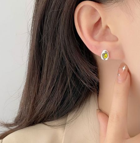 Una vista ravvicinata di una donna che indossa un orecchino in argento sterling 925 con una vivace pietra di zirconia cubica gialla, che mette in mostra il suo scintillio e la vestibilità.